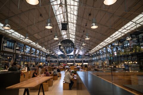 Wooden benches, diners and food counters sit beneath the skylit iron roof of Lisbon’s Time Out Market.