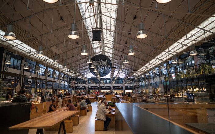Wooden benches, diners and food counters sit beneath the skylit iron roof of Lisbon’s Time Out Market.